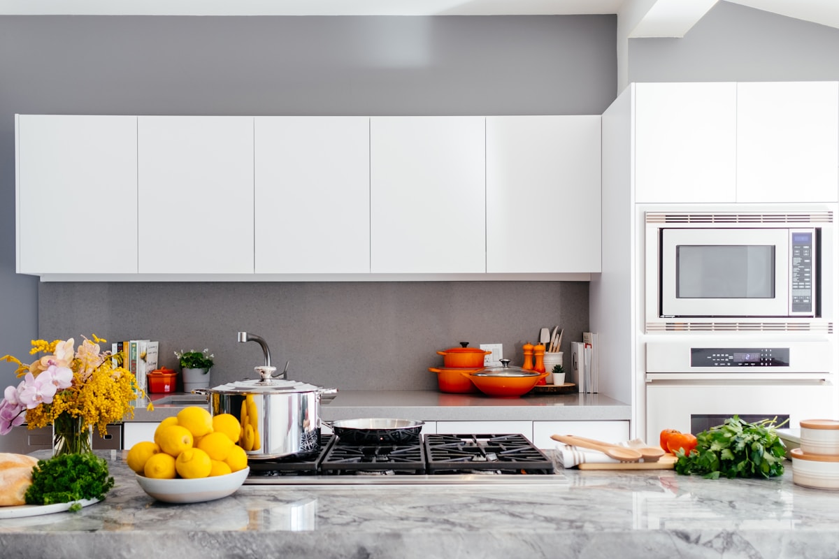 Dapur modern dengan kompor, panci, oven, dan bahan pangan di meja